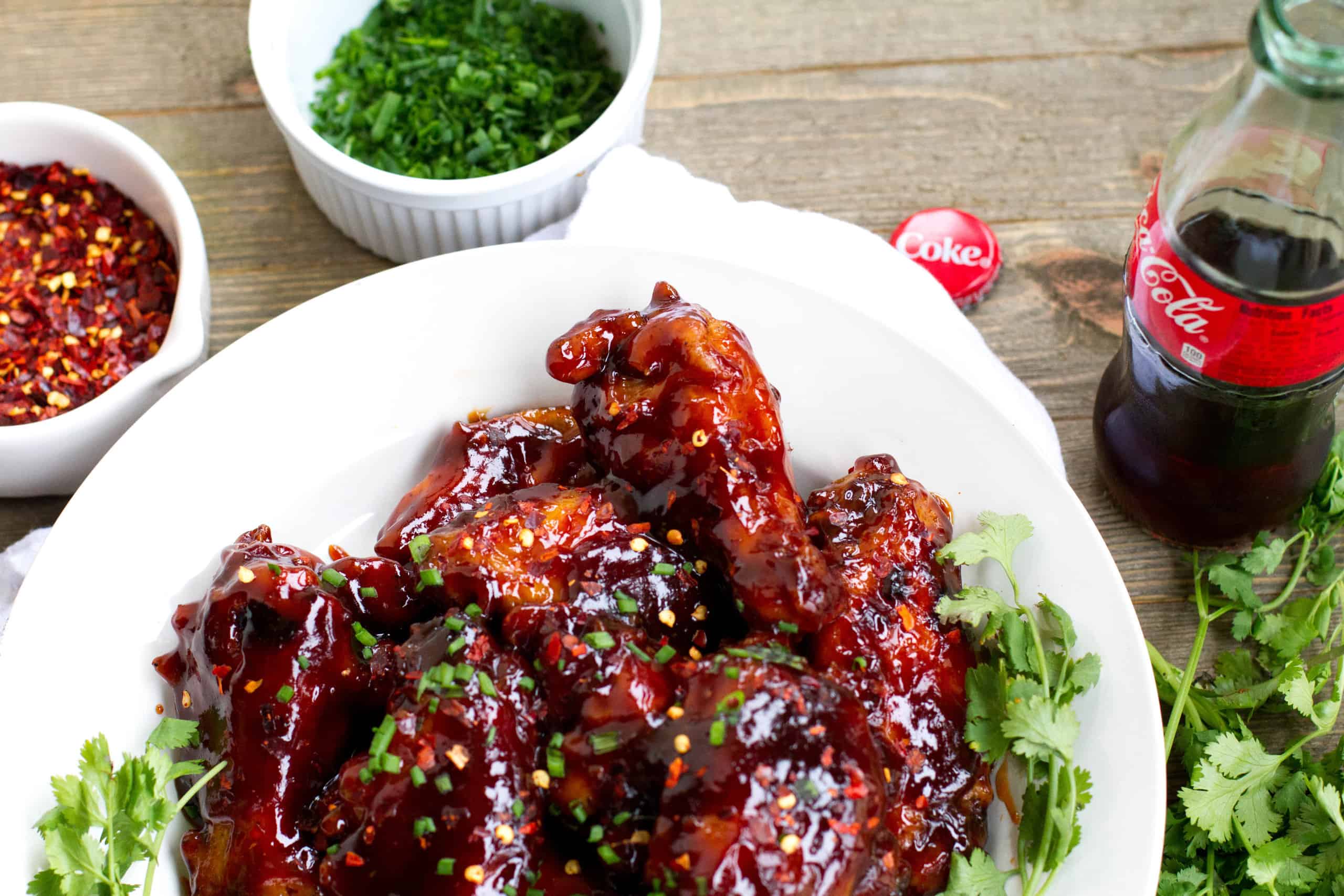 Spicy coca-cola wings on a a plate with a bottle of coke