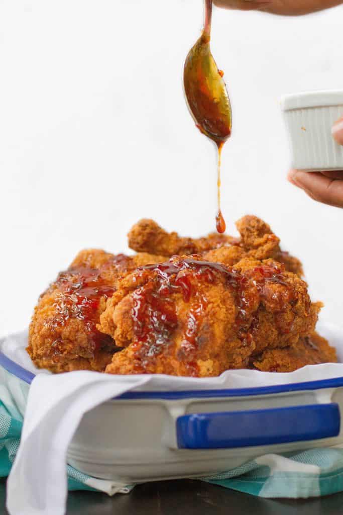 Spooning pepper jelly sauce on top of fried chicken