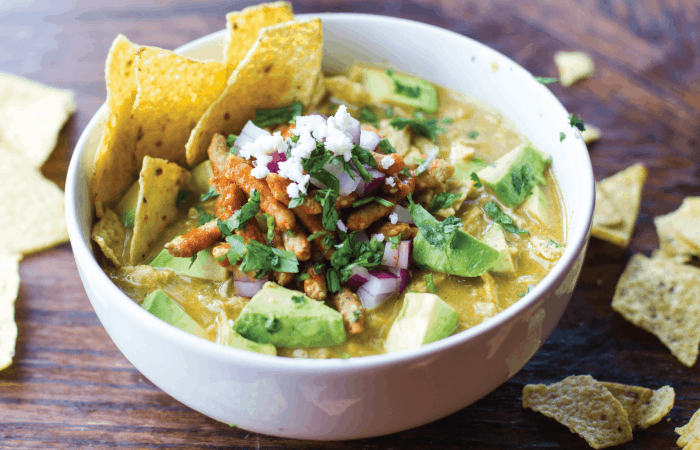 a bowl of Green Chicken Tortilla Soup with pieces of of tortilla chips