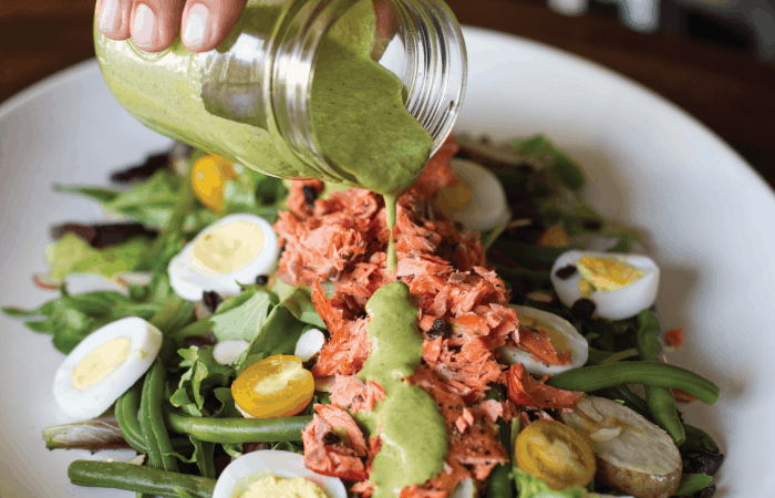 creamy green dressing poured onto salad