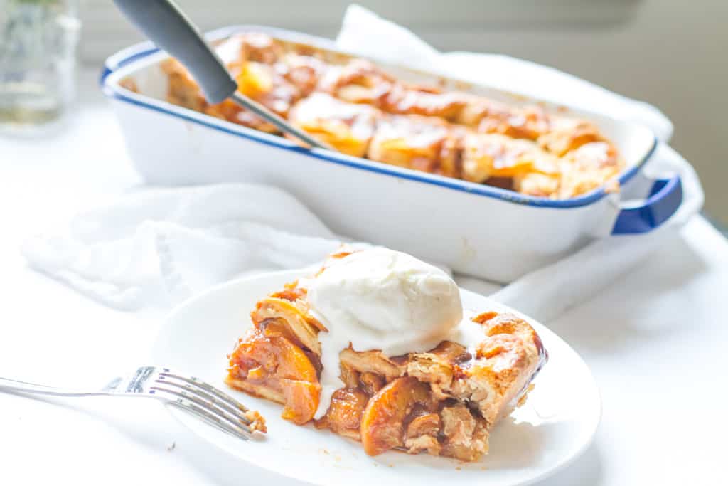 slice of Candied Bourbon Peach Cobbler topped with ice cream