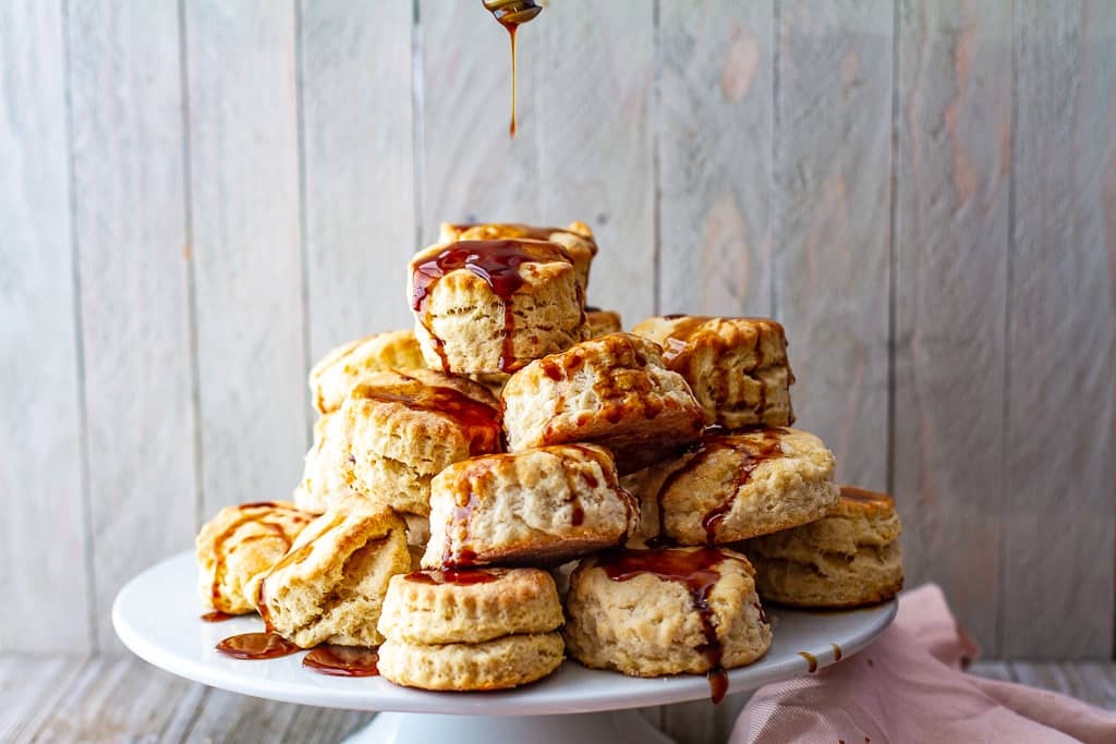 Buttermilk biscuits drizzled with hot buttered rum sauce on platter.