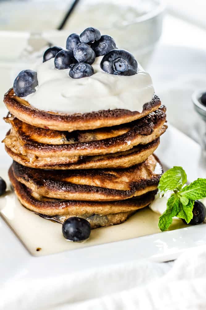 Stack of Blueberry Lemon Keto Pancakes topped whipped cream and fresh blueberries.