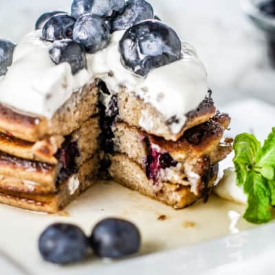 Cut into a stack of Blueberry Lemon Keto Pancakes topped whipped cream and fresh blueberries.