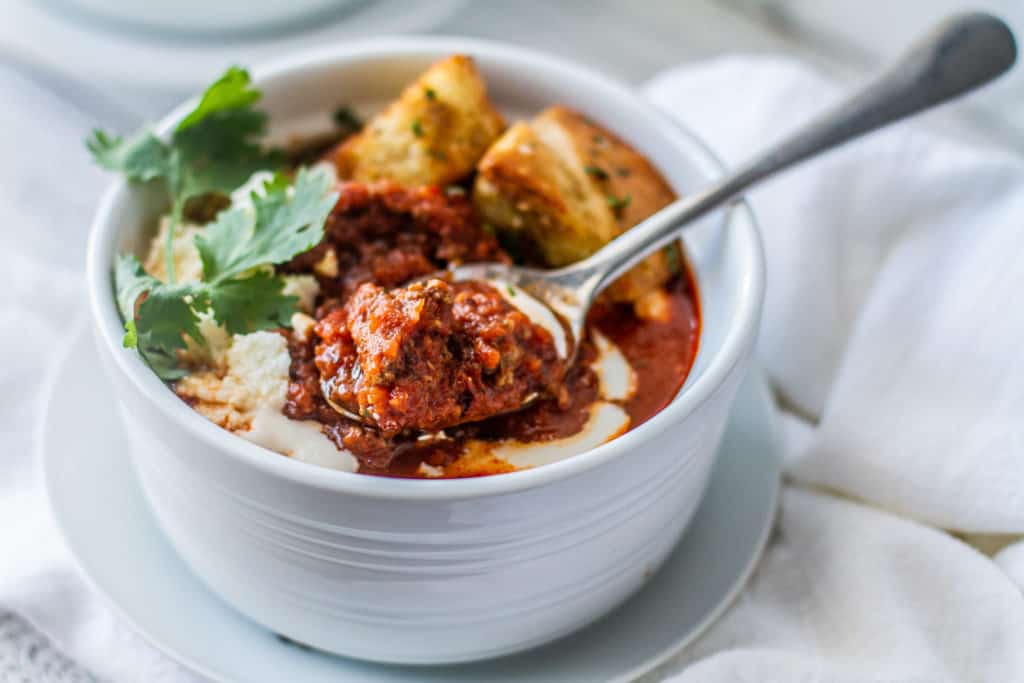 smoky beef and tomato soup on a spoon with croutons