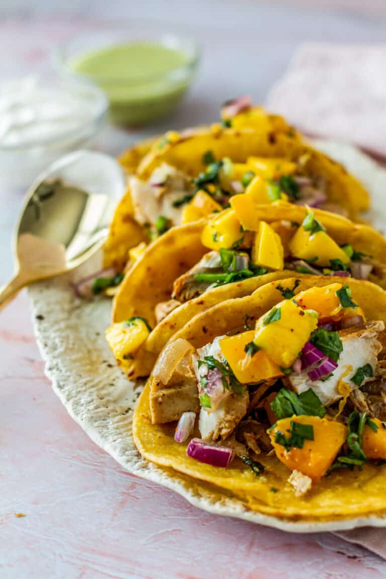 Angled close up of three Spicy Citrus Fish Tacos with Mango Salsa on a serving tray.