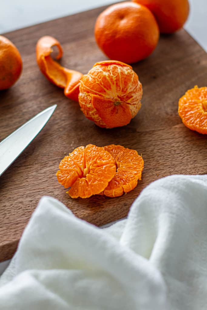 partially peeled clementines on cutting board for detox glow bowl