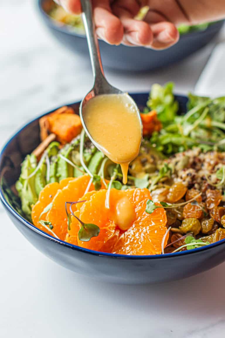 drizzling clementine miso vinaigrette on detox glow bowl