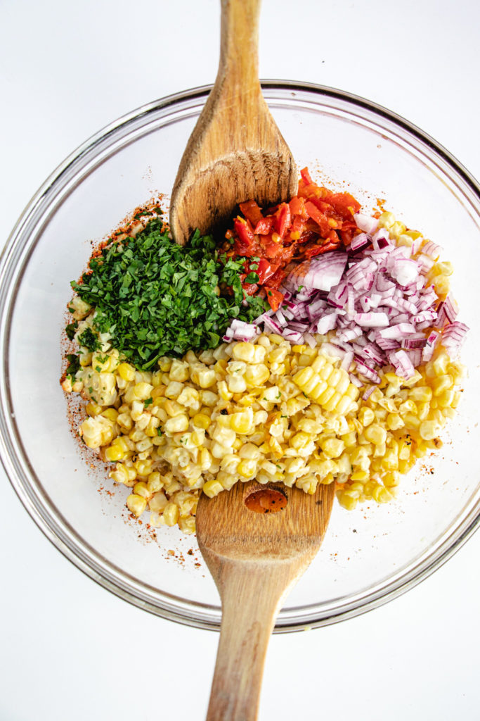 ingredients to mix corn salsa include roasted corn, calabrian peppers, cilantro, red onion and dressing