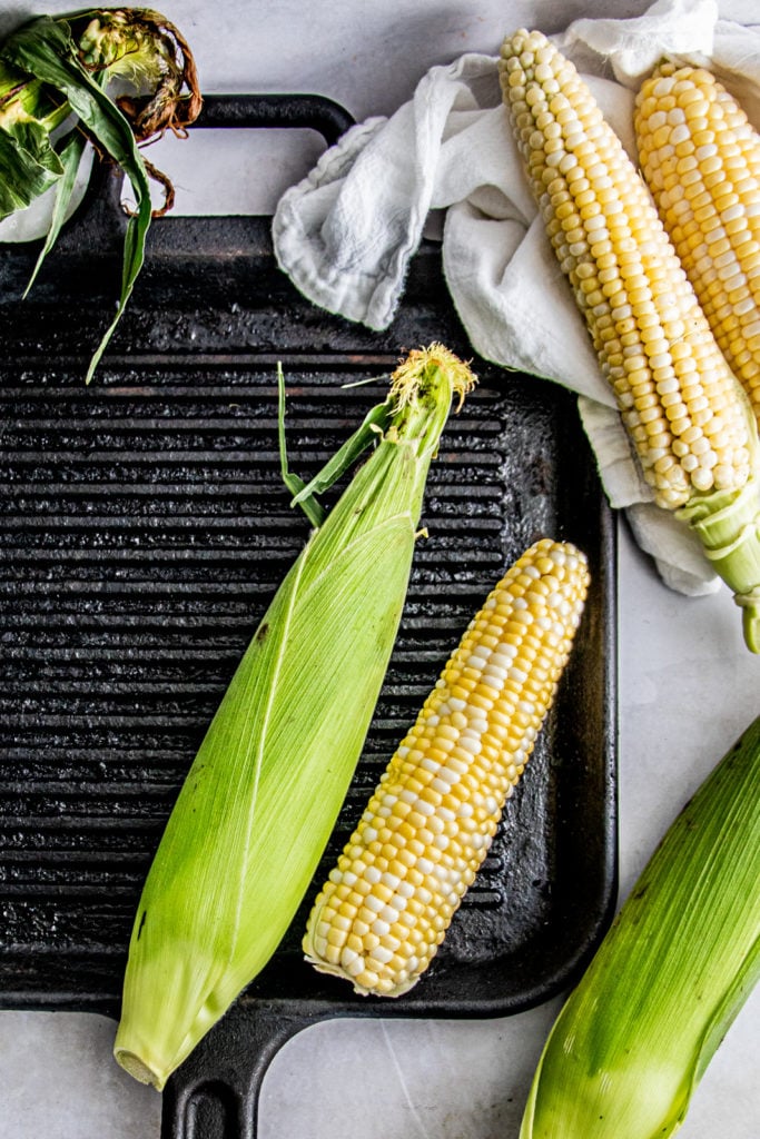 An ear of corn and corn on the cob on a grill pan