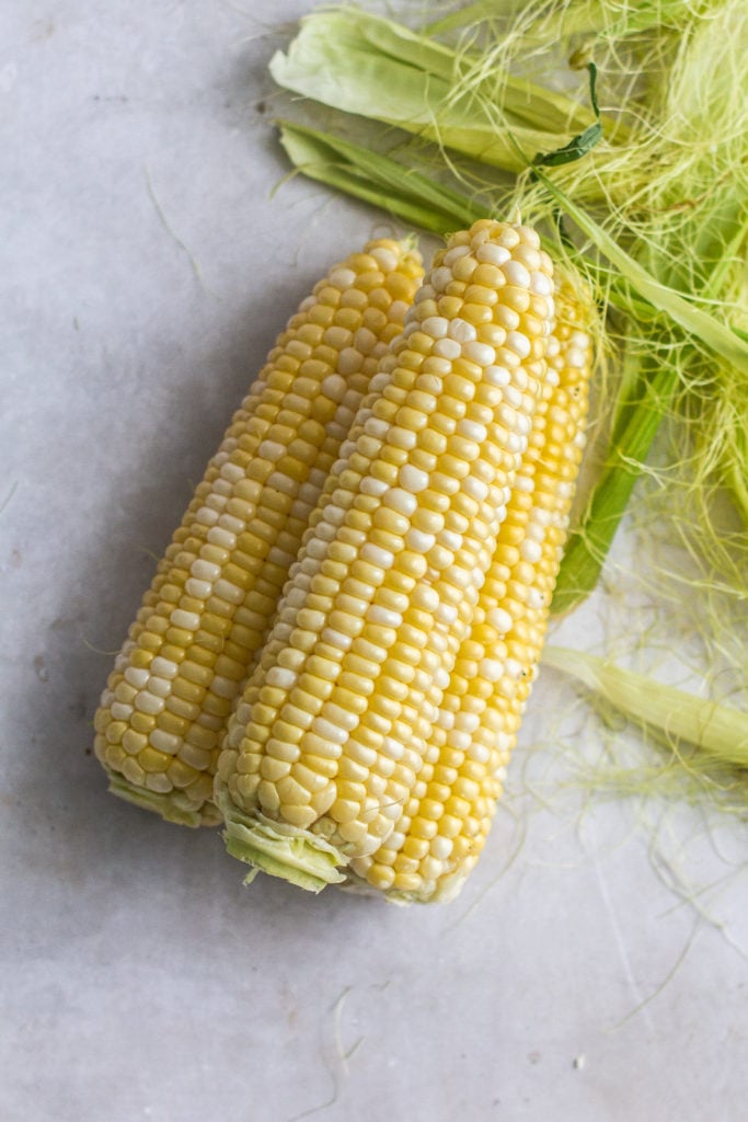 ears of corn next to corn husks