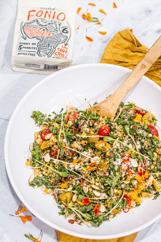 large bowl of summer vegetable & fonio salad next to a package of Yolele fonio