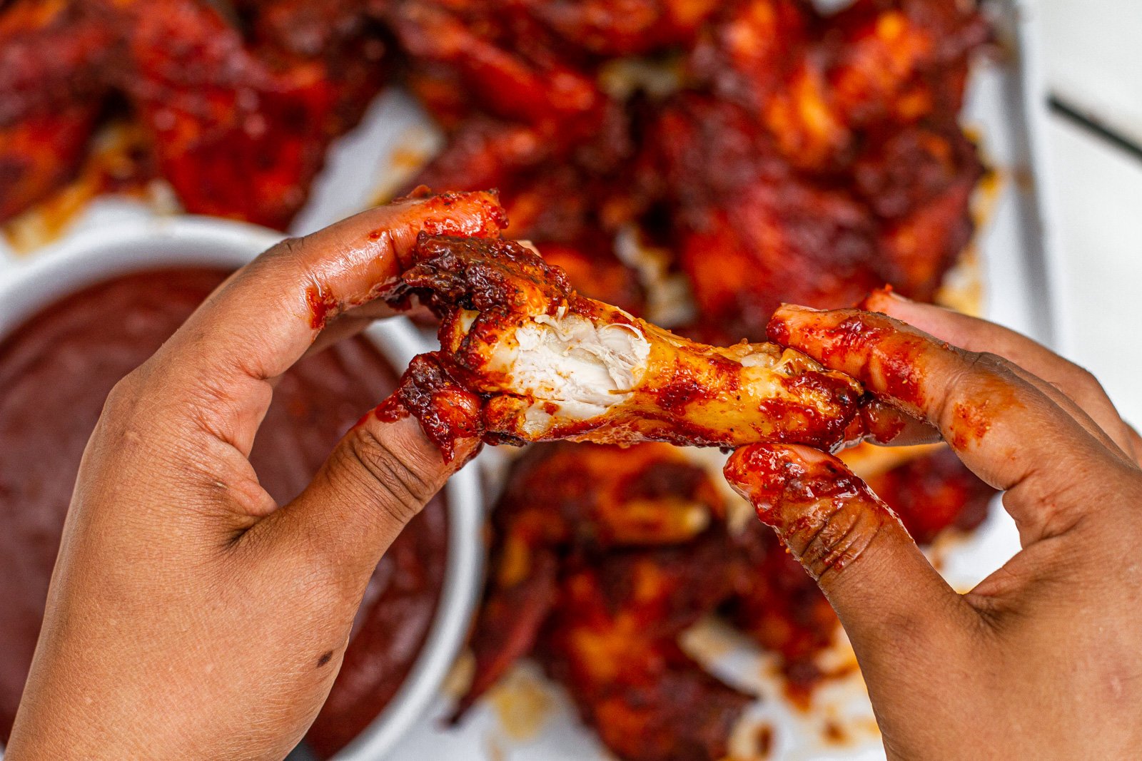 messy hands holding a kansas city bbq chicken wing