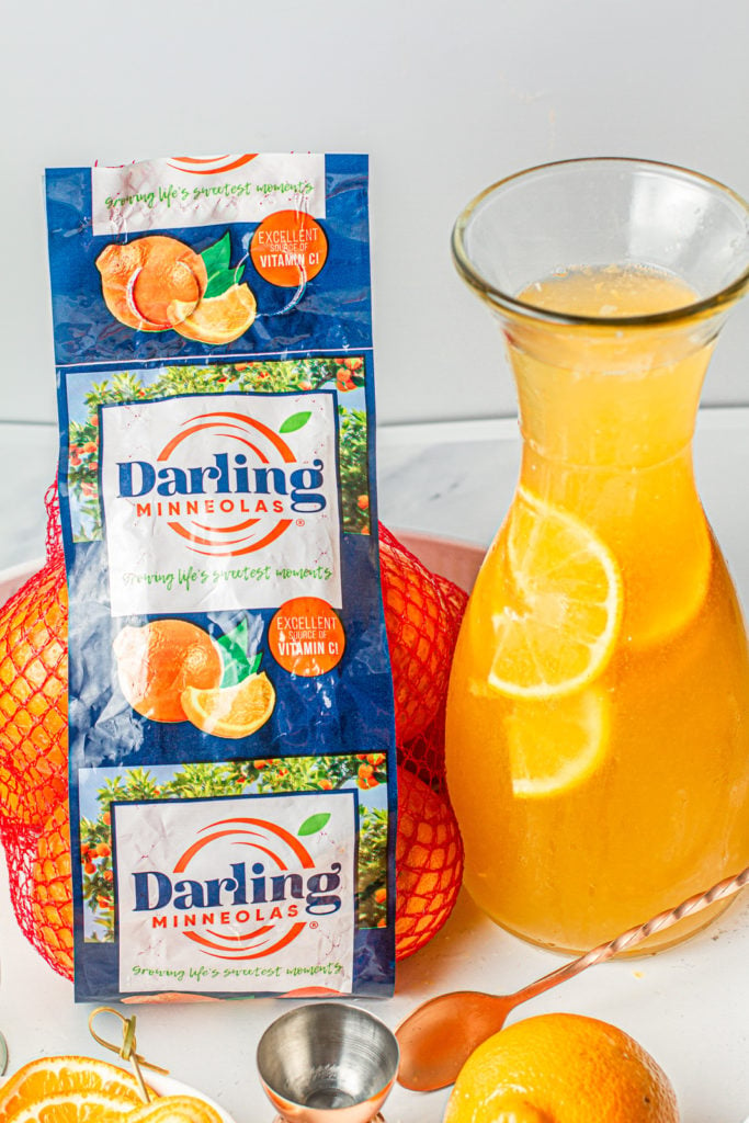 Bag of darling minneolas next to a carafe of minneola paloma