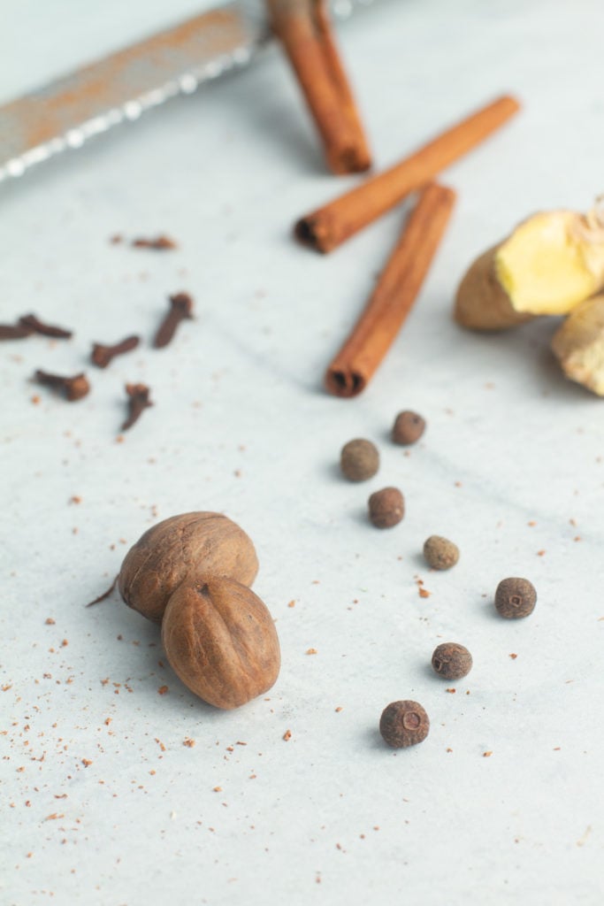 Raw pumpkin spice ingredients whole nutmeg, whole allspice cloves, cinnamon sticks, whole ginger, whole cloves