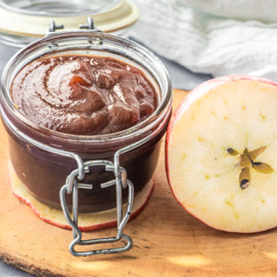 homemade apple butter in jar next to apple