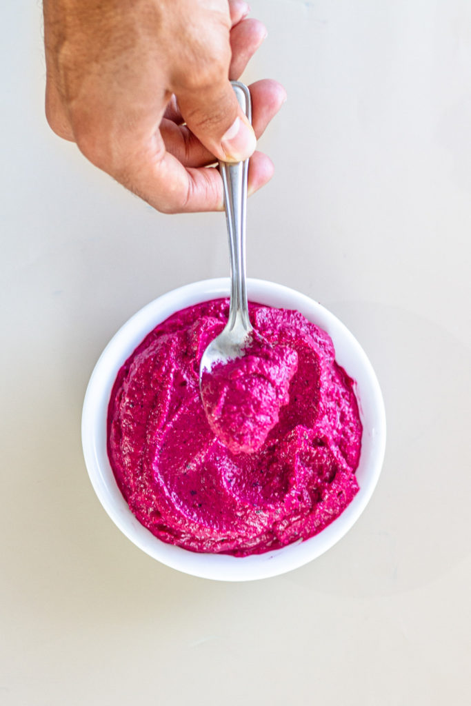 beet pesto sauce in a white bowl with a spoon