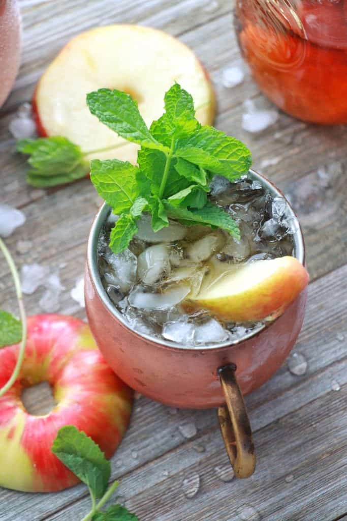 Apple Mint Julep with ice in cooper mug garnished mint and and slice of apple