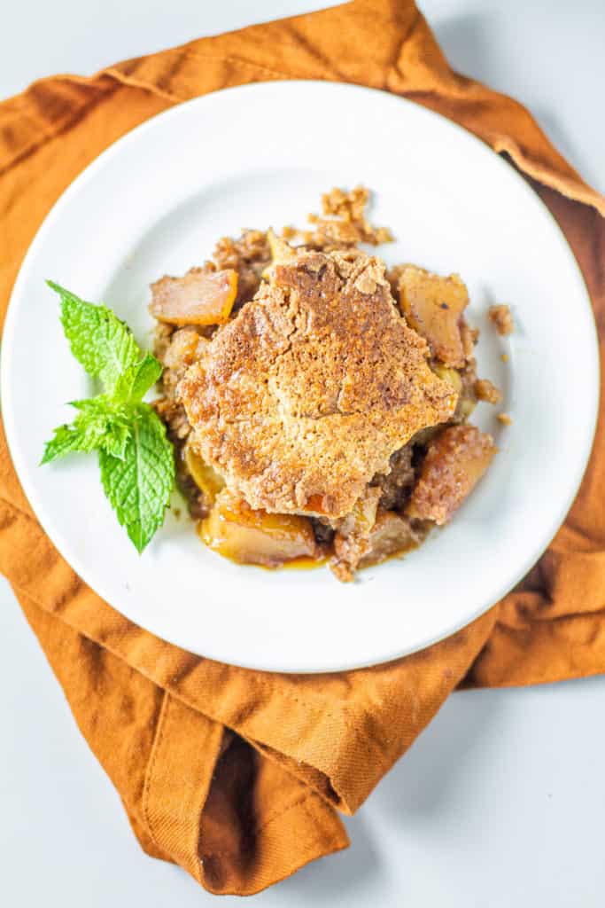 Homemade apple dump cake on plate with sprig of mint
