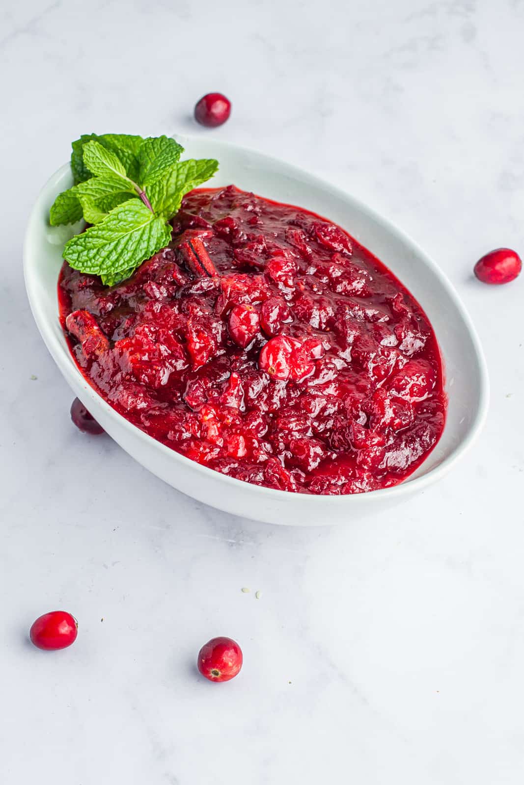 Cranberry sauce garnished with mint in a glass serving dish