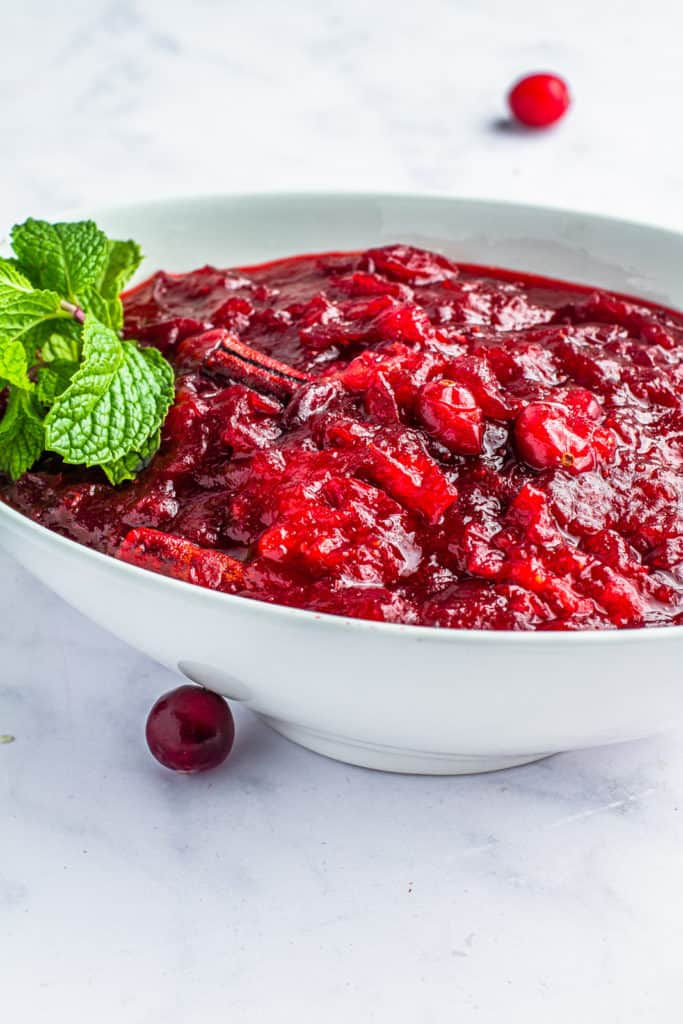 Close up of cranberry sauce garnished with mint in a glass serving dish