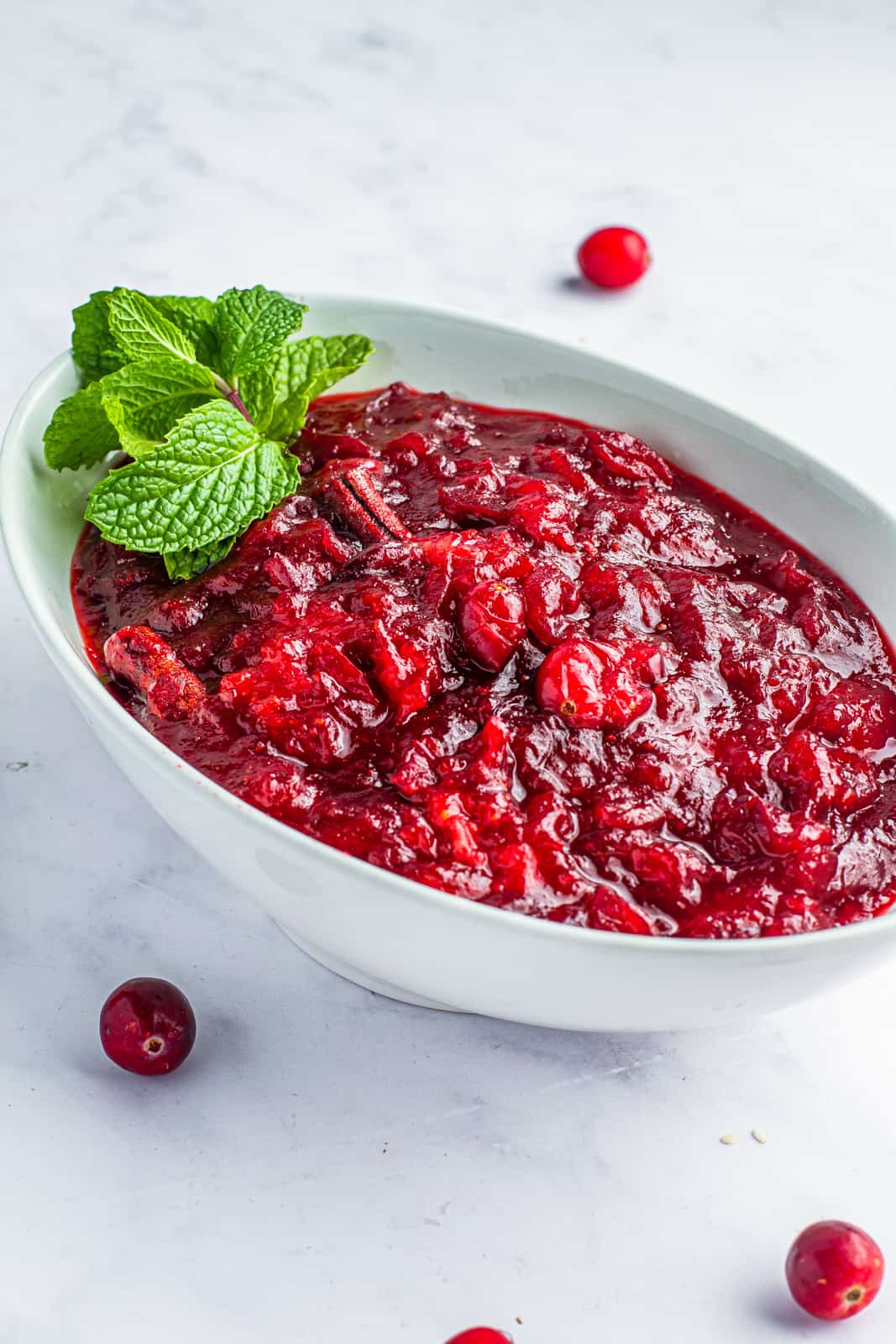 Cranberry sauce garnished with mint in a glass serving dish