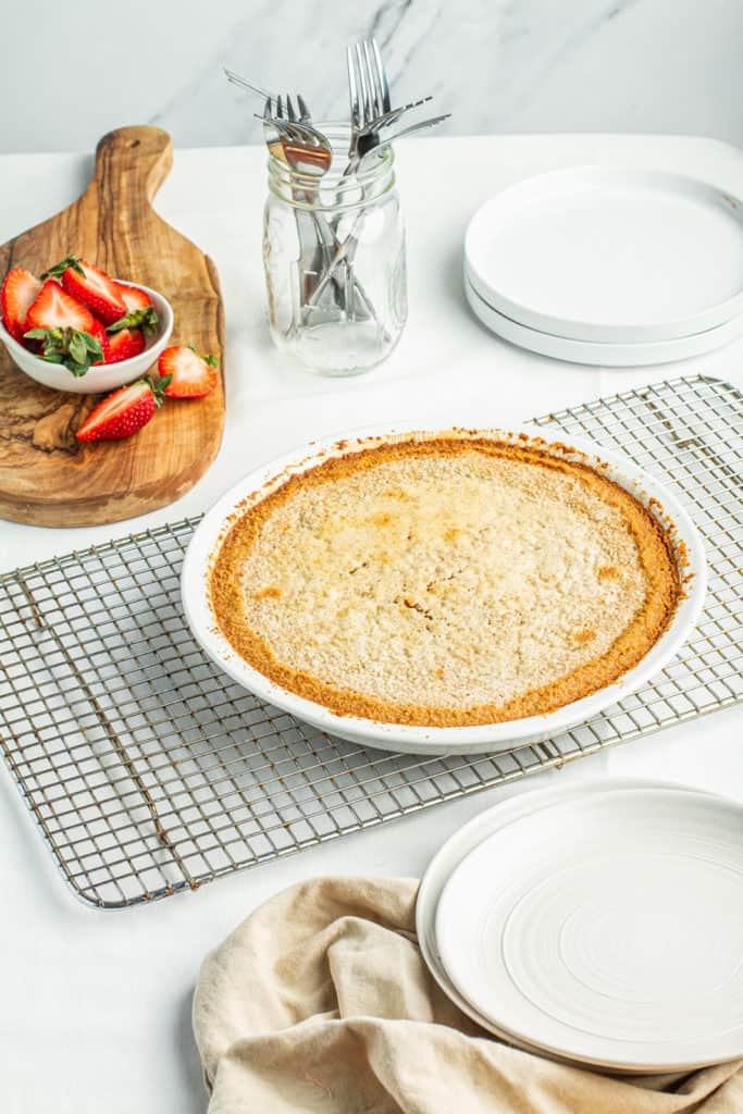 Freshly baked goatmilk pie cooling on rack next to strawberries