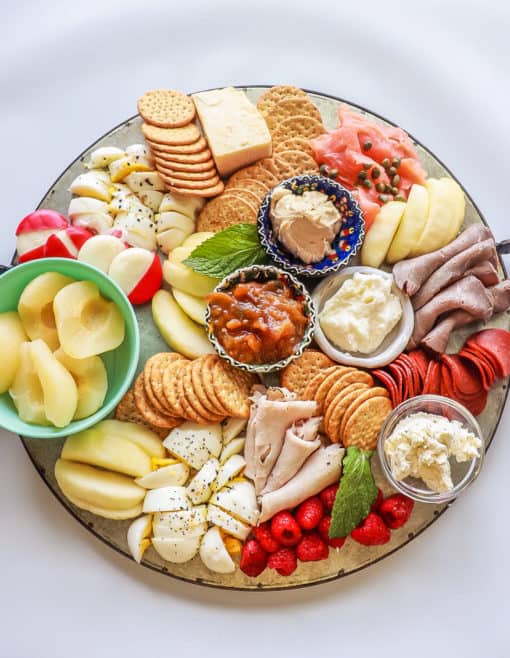 grazing board with deli meat, fruit, crackers, dips, and cheese on counter