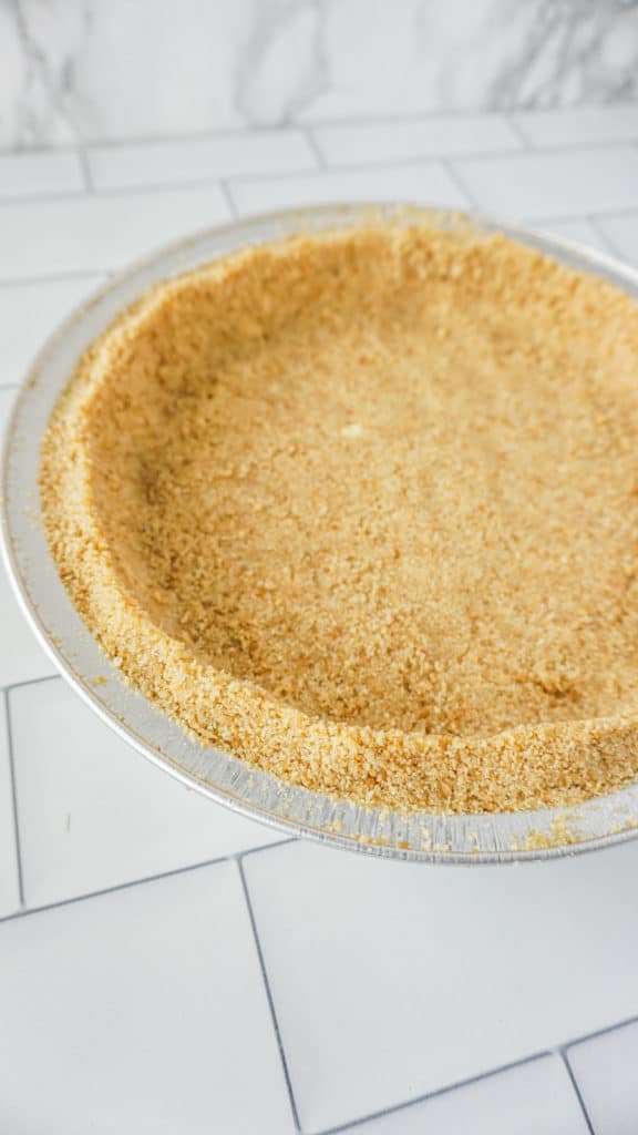graham cracker crust pressed into a pie tin on counter