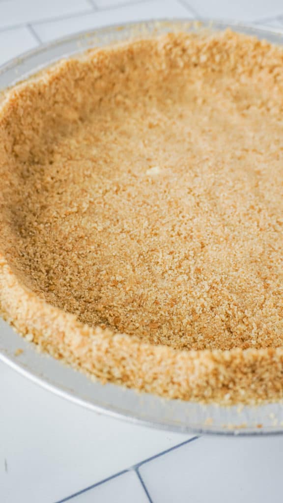 close up of graham cracker crust pressed into a pie tin on counter