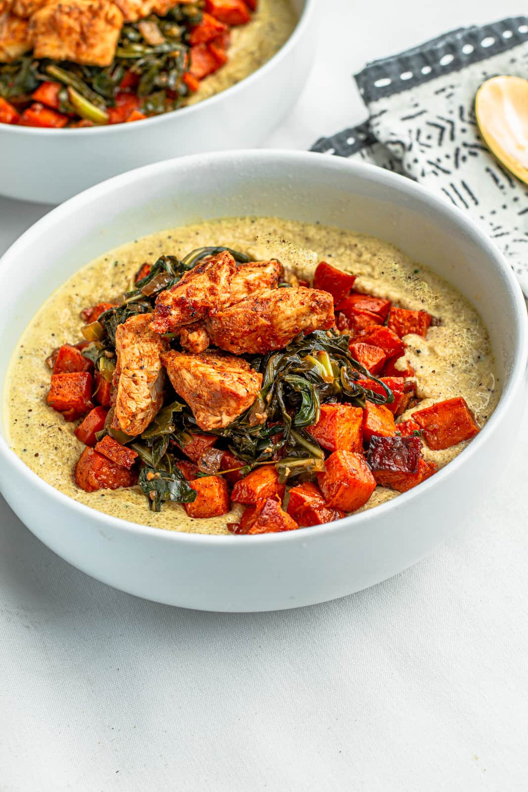 soul bowl with creamy fonio grits, collard greens, chicken bits and maple glazed sweet potatoes