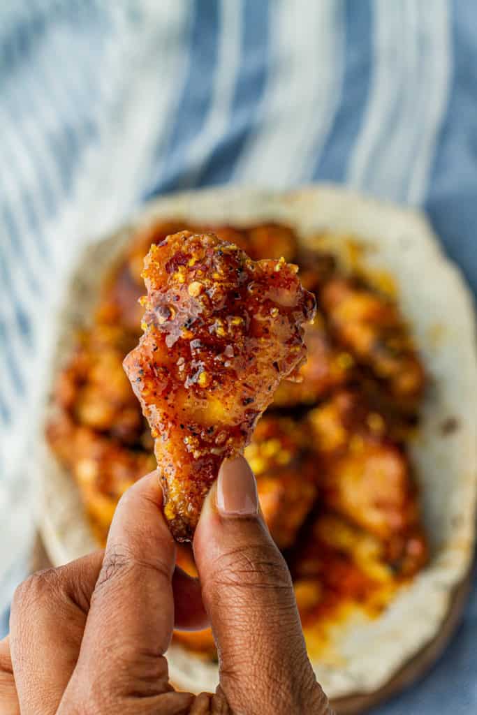 Hot Honey Lemon Pepper Wings on a platter and close up of hand holding a wing