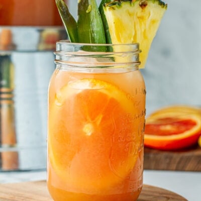 Mason jar of Jungle Juice (Party Punch) garnished with pineapple and a slice of orange