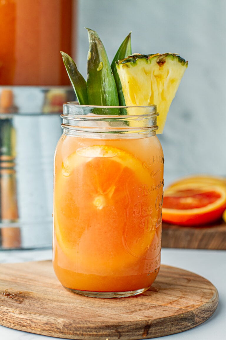 Mason jar of Jungle Juice (Party Punch) garnished with pineapple and a slice of orange