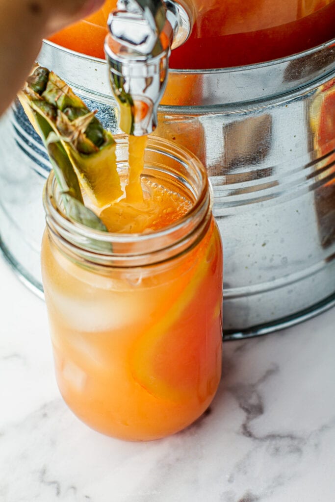 overhead view of Jungle Juice (Party Punch) poured into mason jar garnished with pineapple and a slice of orange