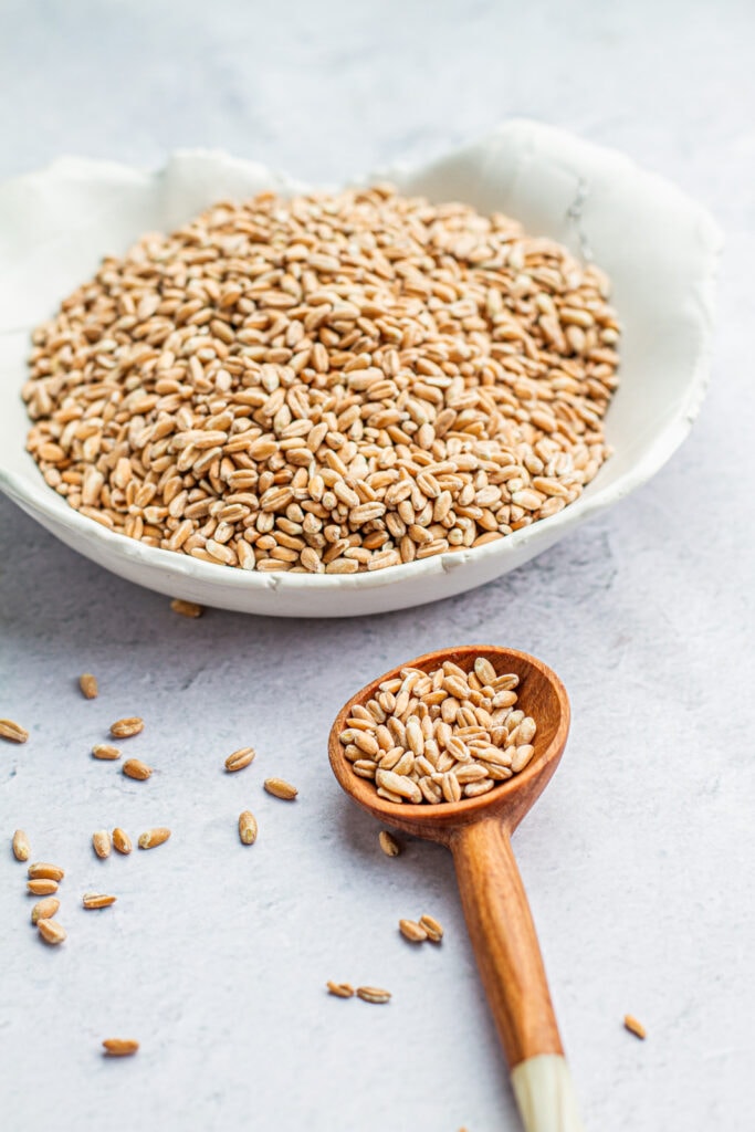 dry farro in a bowl and a wooden full of dry farro