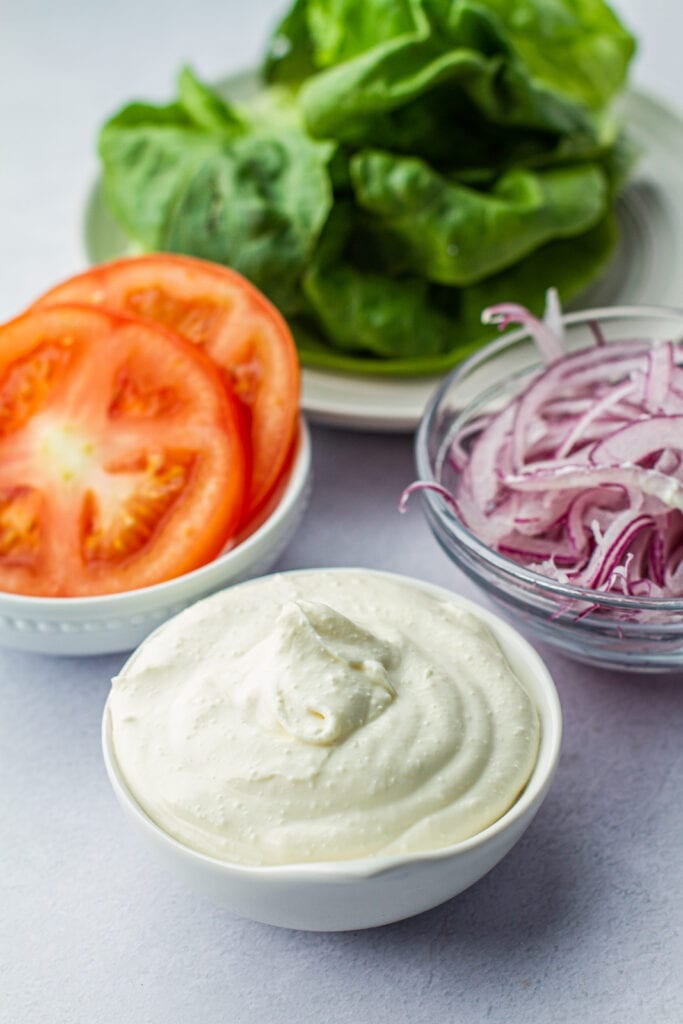 toppings for fresh salmon burger: whipped feta, red onion, tomatoes and lettuce