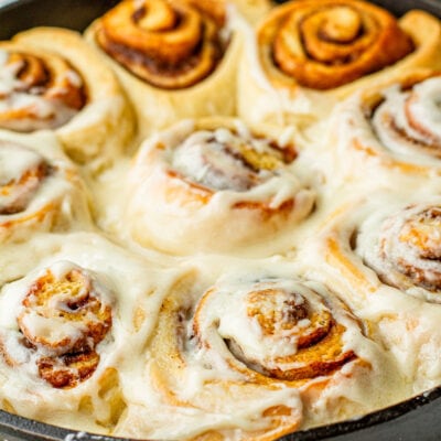 close up of frosted cast iron buttermilk cinnamon rolls
