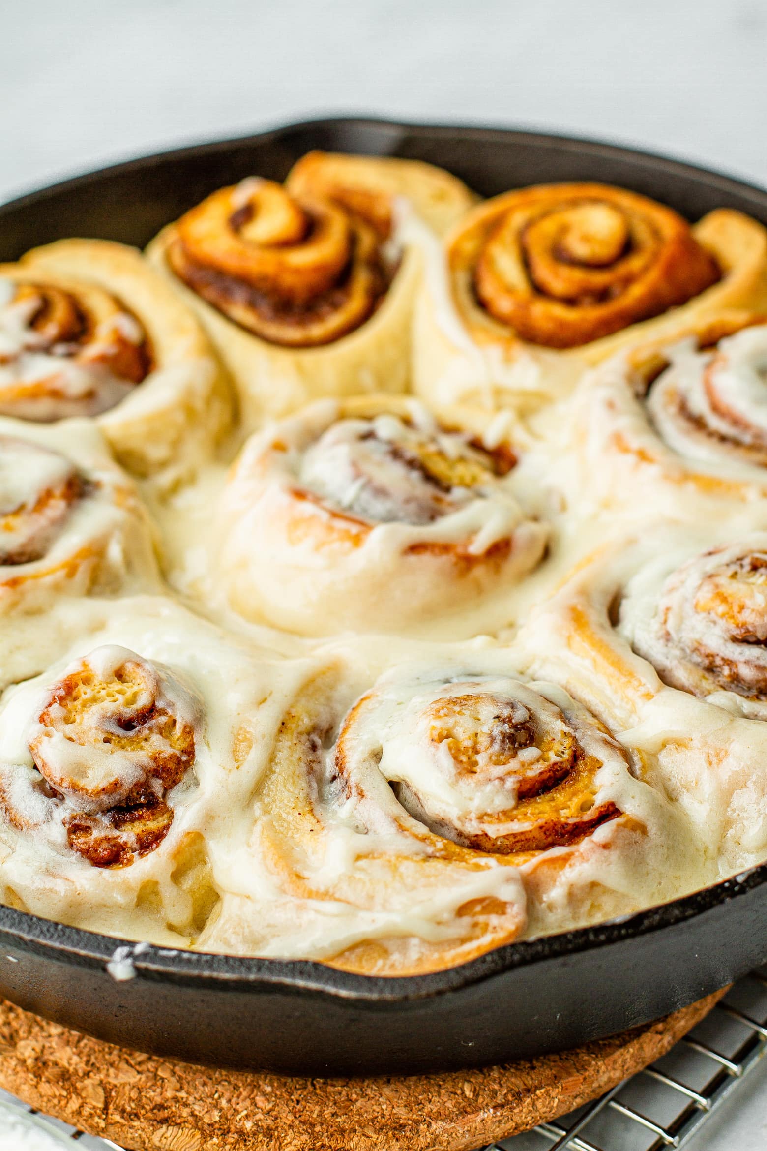 close up of frosted cast iron buttermilk cinnamon rolls