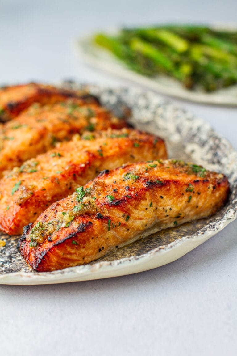 Side angle of Honey Garlic Air Fryer Salmon on a platter next to asparagus