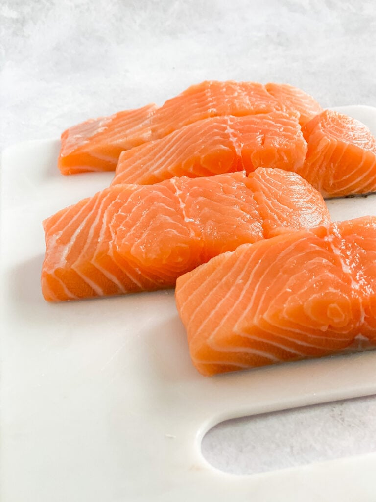 Fresh 6 oz salmon fillets on cutting board