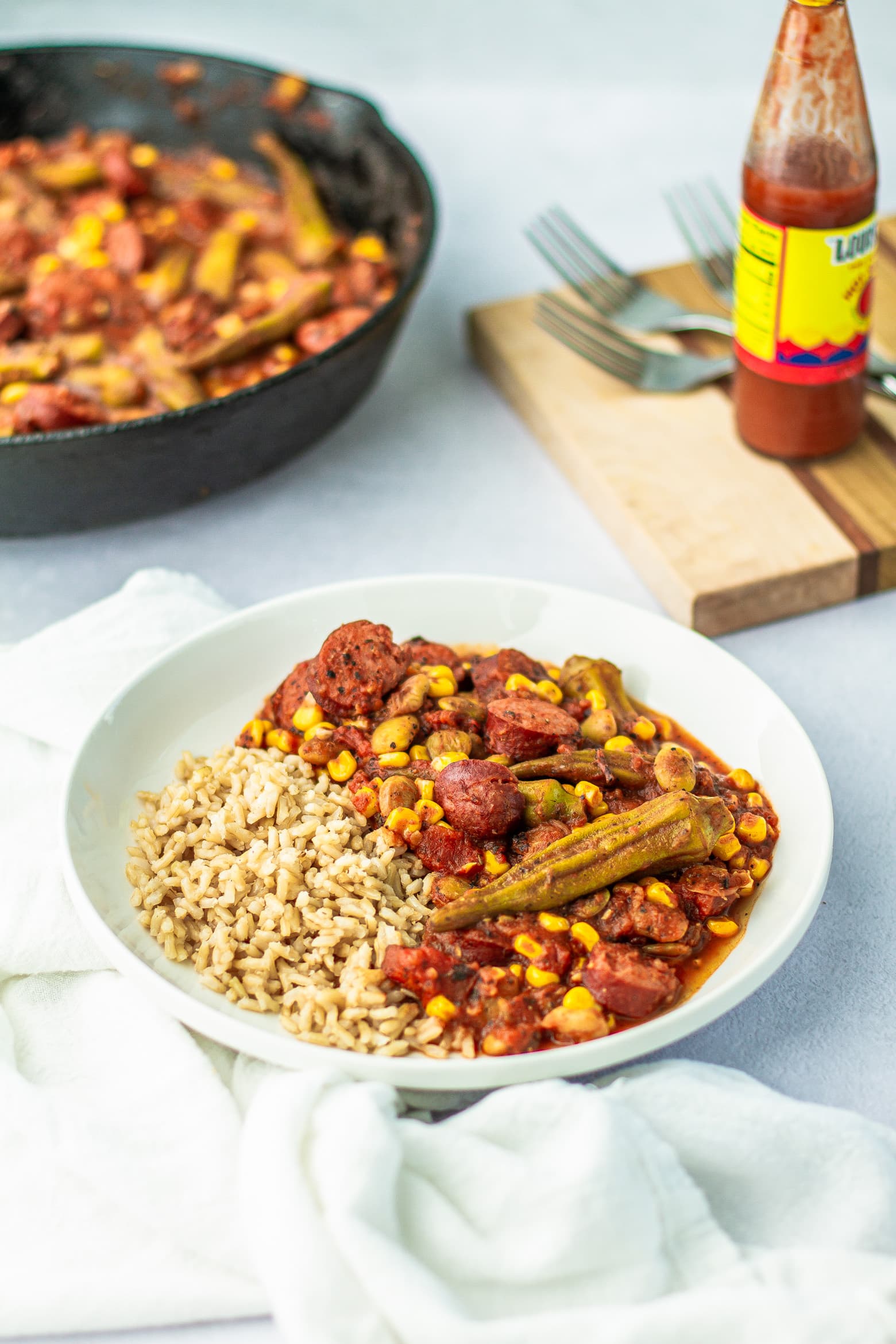 Creole Okra & Tomatoes in a bowl next to Louisiana hot sauce