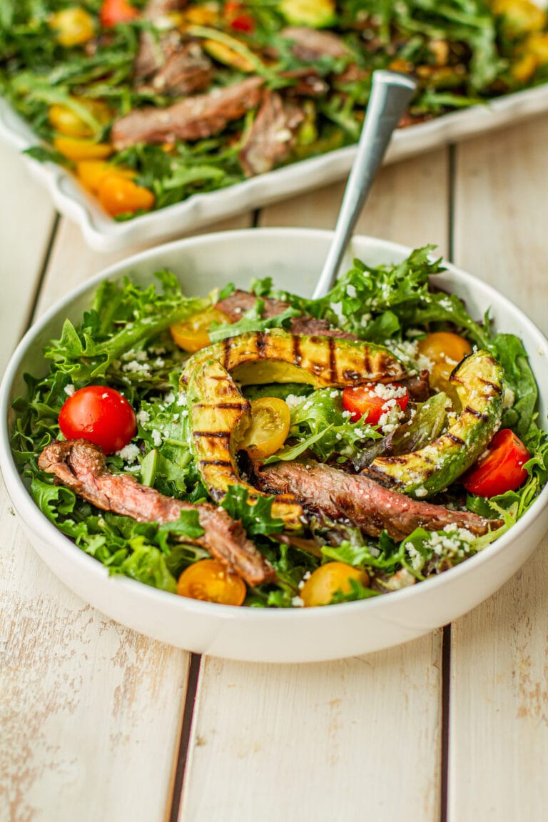 Grilled Avocado & Carne Asada Salad in a white bowl with a fork