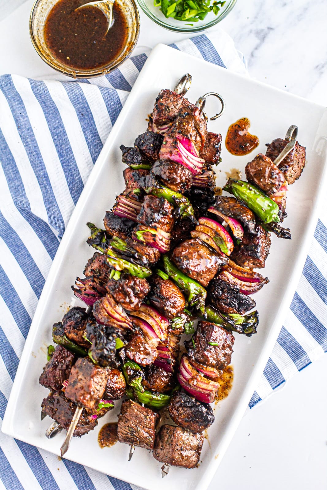 Overhead of Grilled Steak Kabob glazed with Whiskey and Coke on a platter on top of a blue and white cloth