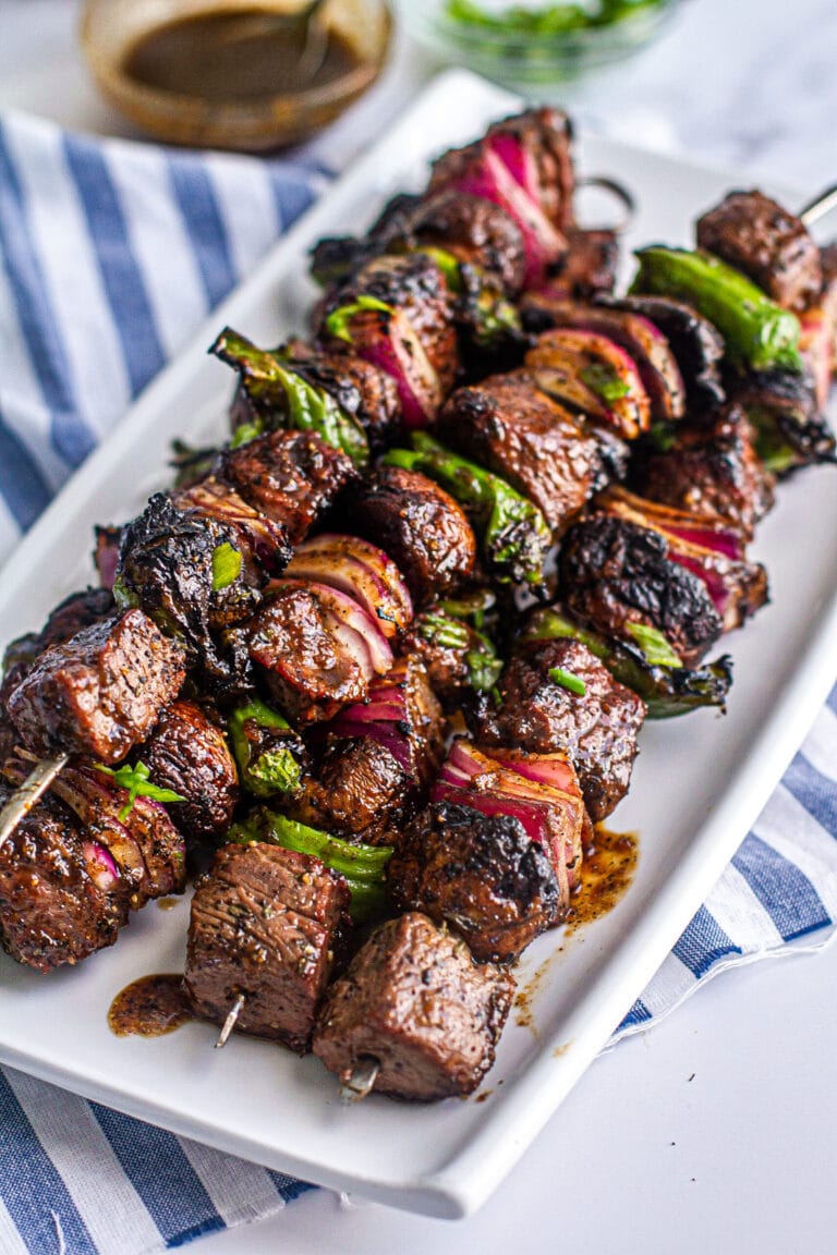Close Up of Grilled Steak Kabob glazed with Whiskey and Coke on a platter on top of a blue and white cloth