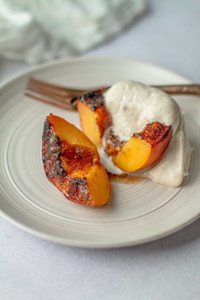 close up Brown Sugar Grilled Peaches with brown sugar whip on a plate with fork
