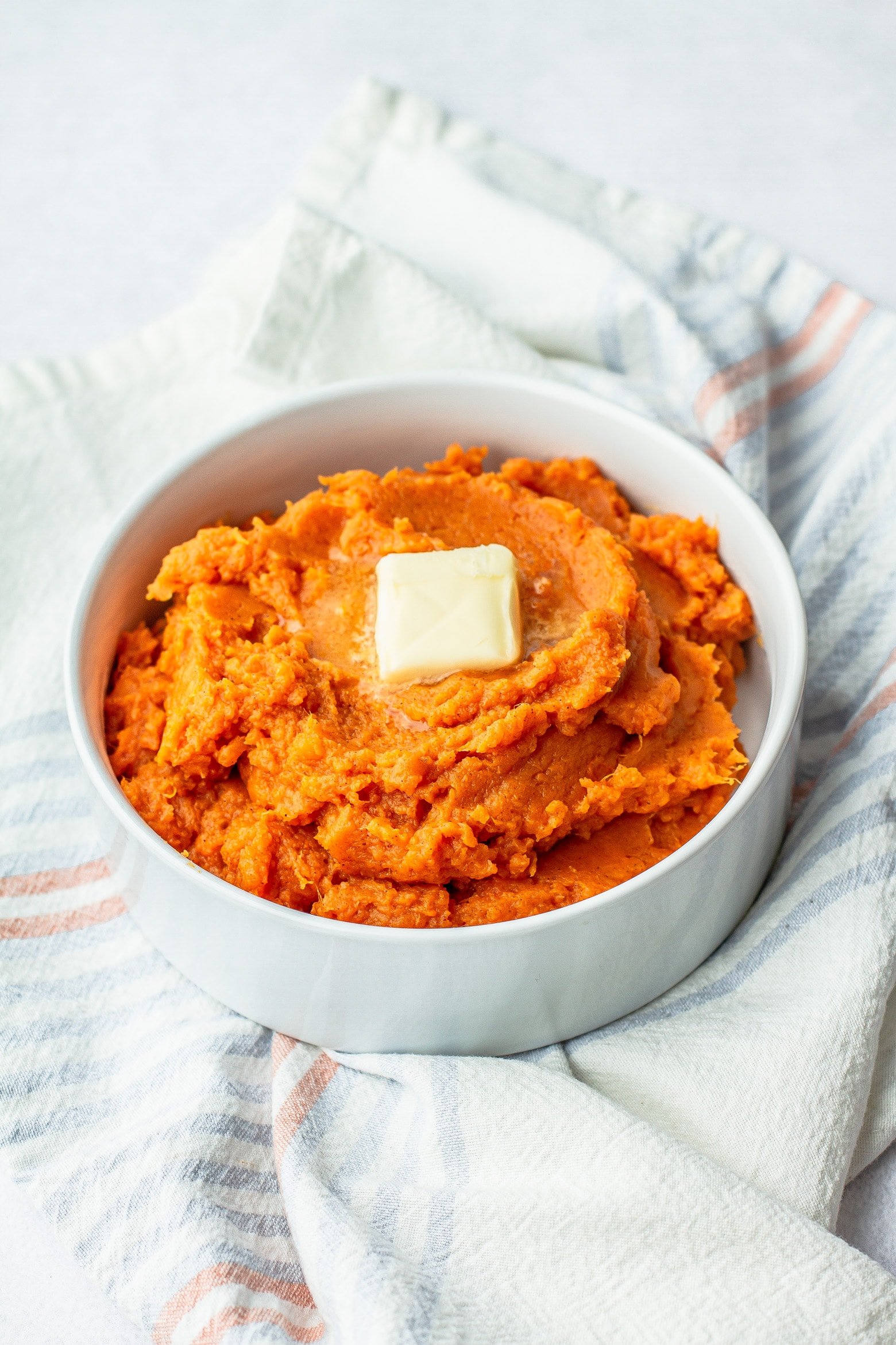 mashed sweet potatoes in a white bowl with a pat of butter