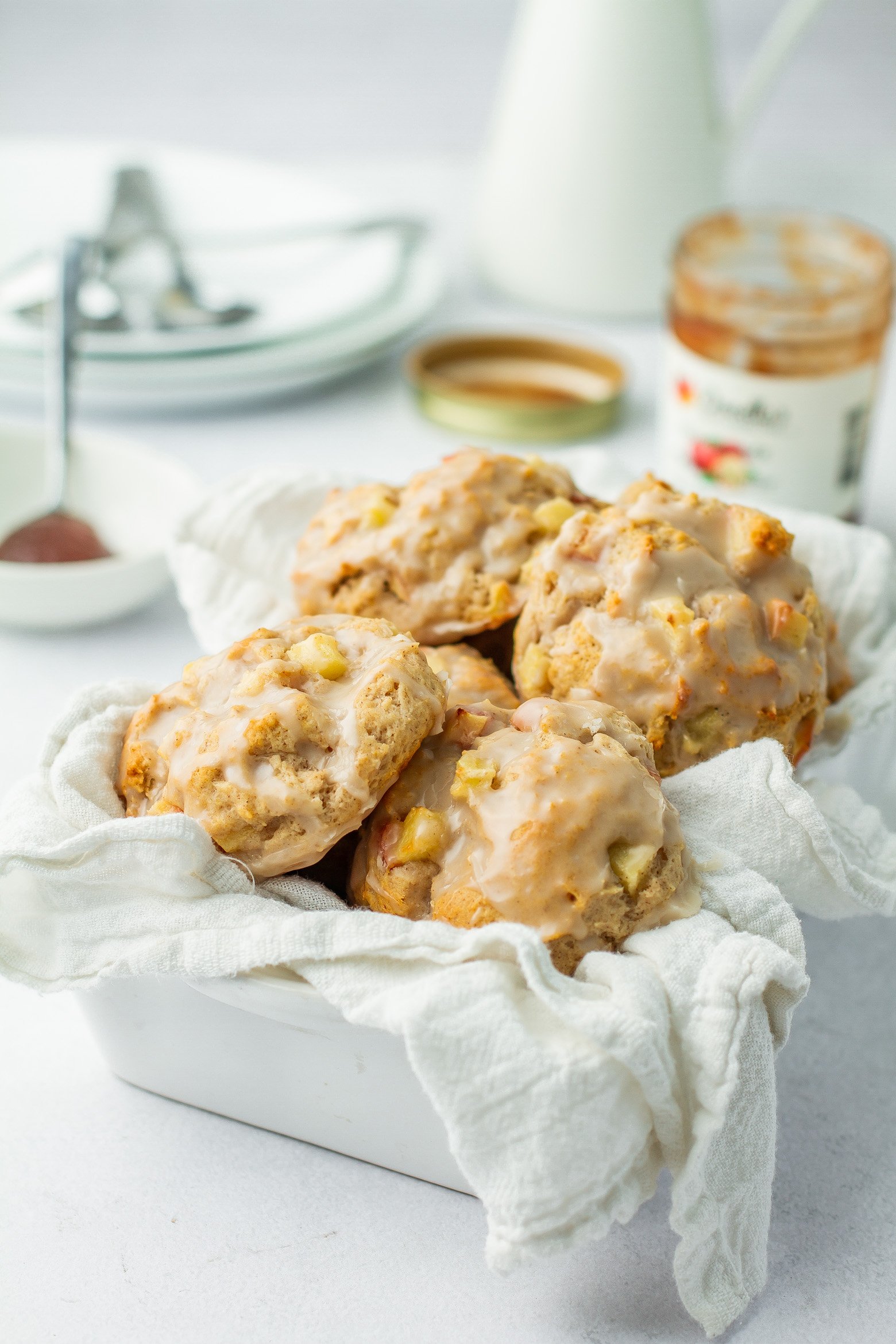 close up of baked apple cinnmon biscuits glazed in a white dish