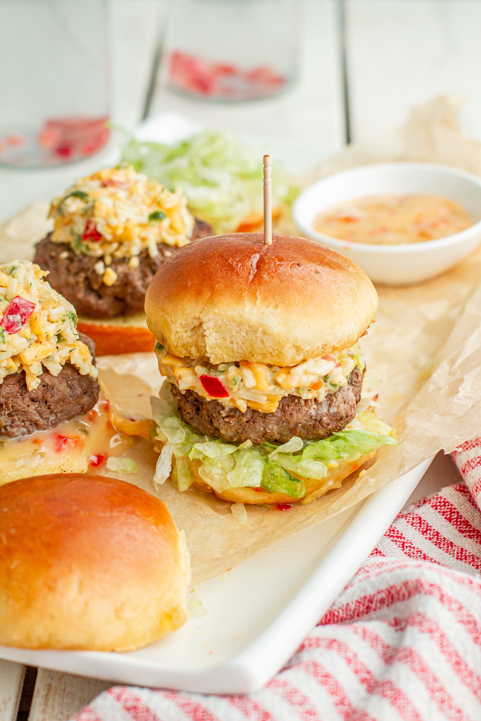 pimento cheese sliders with a toothpick through the bun on a serving tray