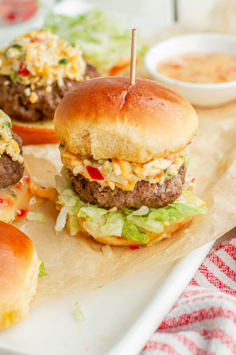 pimento cheese sliders with a toothpick through the bun on a serving tray